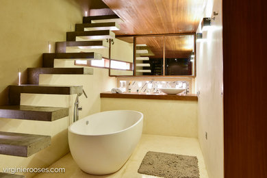 Cette image montre une petite salle de bain principale design avec une baignoire indépendante, un mur beige, une vasque et un plan de toilette en bois.