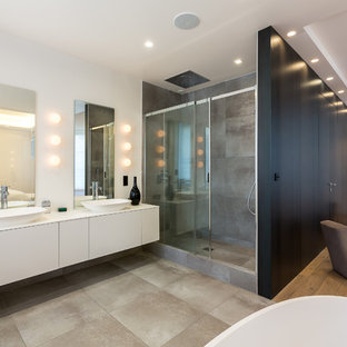 Réalisation d'une grand douche en alcôve principale design avec un placard à porte plane, des portes de placard blanches, une baignoire indépendante, un carrelage marron, un mur blanc, une vasque et une cabine de douche à porte coulissante.
