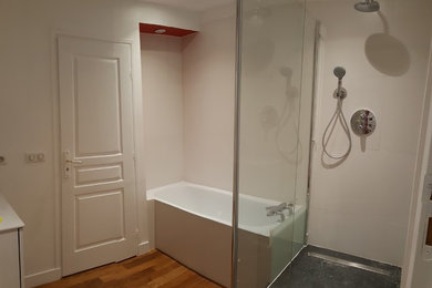 Réalisation d'une salle de bain principale design de taille moyenne avec des portes de placard blanches, un combiné douche/baignoire, un mur blanc, un sol en bois brun, un lavabo encastré et aucune cabine.