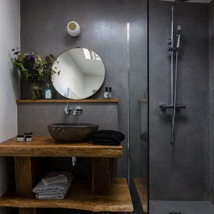 Cette image montre une petit salle de bain principale design avec une douche à l'italienne, un mur gris, béton au sol, un plan de toilette en bois, un sol gris, un placard sans porte, des portes de placard en bois brun, une vasque, aucune cabine et un plan de toilette marron.
