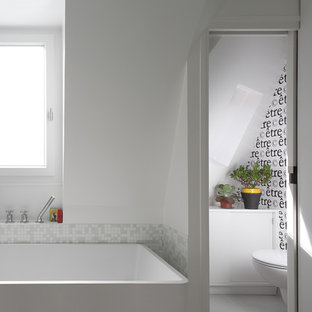 Inspiration pour une petit douche en alcôve principale design avec un placard à porte affleurante, des portes de placard blanches, une baignoire indépendante, un WC séparé, un carrelage blanc, carrelage en mosaïque, un mur blanc, un sol en carrelage de céramique et un lavabo suspendu.