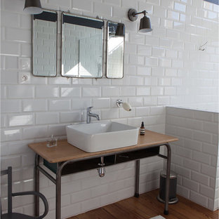 Idée de décoration pour une salle de bain principale urbaine de taille moyenne avec une vasque, un plan de toilette en bois, un carrelage blanc, un carrelage métro, un mur noir, un sol en bois brun et un plan de toilette marron.