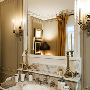 Idée de décoration pour une grand salle de bain principale victorienne avec des portes de placard en bois brun, un mur beige, un lavabo encastré et un plan de toilette en marbre.