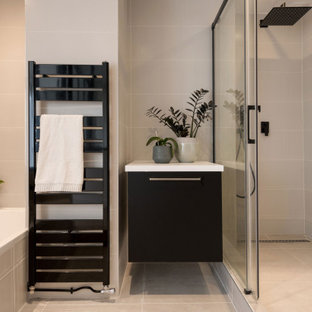 Idée de décoration pour une douche en alcôve principale design de taille moyenne avec des portes de placard noires, des carreaux de céramique, un plan de toilette en surface solide, un plan de toilette blanc, une cabine de douche à porte coulissante, un placard à porte plane, une baignoire posée, un carrelage gris et un sol gris.