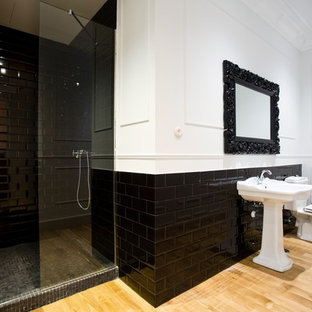 Exemple d'une grand salle de bain tendance avec un lavabo de ferme, un carrelage noir, un mur blanc, un sol en bois clair, un WC à poser et un carrelage métro.