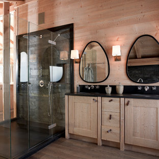 Réalisation d'une salle d'eau chalet de taille moyenne avec un lavabo encastré, un placard à porte shaker, des portes de placard en bois clair, une douche à l'italienne, un carrelage noir, un carrelage de pierre, un mur beige et un sol en bois brun.