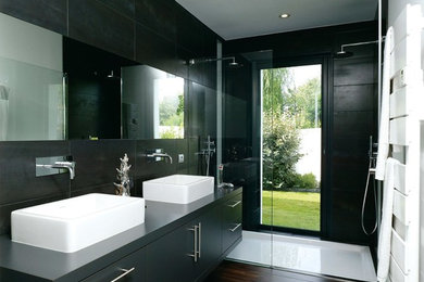 Foto di una stanza da bagno con doccia moderna di medie dimensioni con ante nere, doccia alcova, piastrelle nere, pareti nere, parquet scuro e lavabo a bacinella