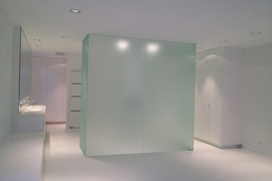 Exemple d'une salle de bain principale tendance de taille moyenne avec un placard à porte affleurante, des portes de placard blanches, une douche ouverte, WC séparés, un carrelage blanc, un mur blanc, un lavabo intégré et un plan de toilette en surface solide.