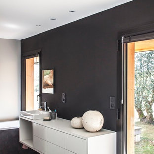 Cette image montre une grand salle de bain principale design avec des portes de placard blanches, un mur noir et une vasque.