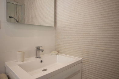Exemple d'une petite salle d'eau tendance avec une douche d'angle, WC suspendus, un carrelage beige, des carreaux de céramique, un mur blanc, un sol beige et une cabine de douche à porte coulissante.