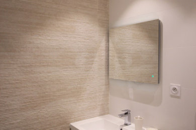 Cette image montre une petite salle d'eau design avec une douche d'angle, WC suspendus, un carrelage beige, des carreaux de céramique, un mur blanc, un sol beige et une cabine de douche à porte coulissante.