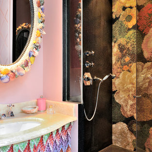 Exemple d'une salle de bain éclectique avec un mur rose, un lavabo encastré, une cabine de douche à porte battante et un plan de toilette beige.