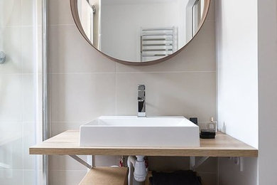 Small contemporary shower room bathroom in Paris with open cabinets, beige cabinets, a built-in shower, a two-piece toilet, grey tiles, stone tiles, grey walls, ceramic flooring, a console sink, wooden worktops, grey floors, a sliding door and beige worktops.