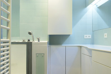 Réalisation d'une petite salle de bain principale design avec un placard à porte affleurante, des portes de placard blanches, un bain bouillonnant, un carrelage bleu, mosaïque, un mur bleu, un sol en carrelage de terre cuite, un lavabo encastré et un plan de toilette en surface solide.