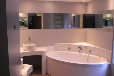 Cette photo montre une salle de bain principale chic avec une baignoire d'angle, un carrelage beige, un mur blanc, un sol en carrelage de céramique et un plan de toilette en carrelage.