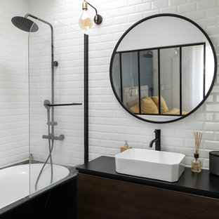 Idée de décoration pour une salle de bain urbaine avec un placard à porte plane, des portes de placard en bois sombre, une baignoire en alcôve, un combiné douche/baignoire, un carrelage blanc, une vasque, un sol noir, aucune cabine et un plan de toilette noir.
