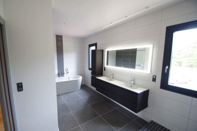 他の地域にある高級な広いモダンスタイルのおしゃれなマスターバスルーム (フラットパネル扉のキャビネット、黒いキャビネット、置き型浴槽、バリアフリー、白いタイル、モザイクタイル、コンソール型シンク、オープンシャワー、白い洗面カウンター、洗面台2つ、フローティング洗面台、白い壁、セラミックタイルの床、グレーの床) の写真