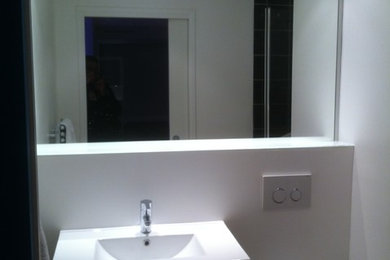 Cette photo montre une salle de bain tendance avec WC suspendus, un carrelage blanc, un mur blanc, parquet en bambou et un lavabo suspendu.