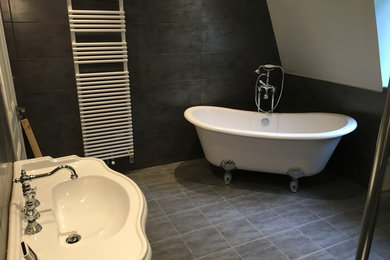Inspiration för 50 tals badrum, med ett badkar med tassar, en kantlös dusch, en vägghängd toalettstol, grå kakel, keramikplattor, grå väggar, klinkergolv i keramik och ett piedestal handfat