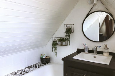 Imagen de cuarto de baño vintage pequeño con puertas de armario beige, bañera encastrada sin remate, baldosas y/o azulejos blancos, baldosas y/o azulejos de cerámica, paredes blancas, suelo vinílico, aseo y ducha, lavabo bajoencimera, encimera de laminado, suelo beige y encimeras negras