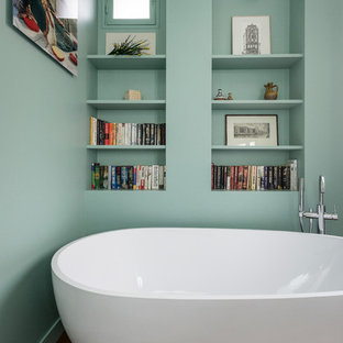 Aménagement d'une petit salle de bain principale contemporaine avec un placard sans porte, une baignoire indépendante, un mur vert et un sol en bois brun.