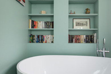 Diseño de cuarto de baño principal contemporáneo pequeño con armarios abiertos, bañera exenta, paredes verdes y suelo de madera en tonos medios