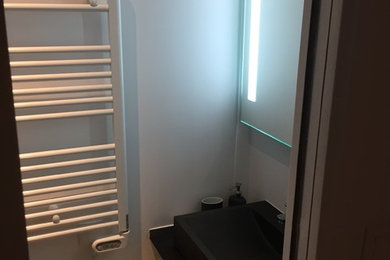 Cette image montre une petite salle de bain minimaliste pour enfant avec un placard à porte plane, des portes de placard blanches, une douche à l'italienne, un carrelage noir, des carreaux de céramique, un mur blanc, sol en stratifié, un plan vasque, un plan de toilette en stratifié, un sol gris et une cabine de douche à porte coulissante.