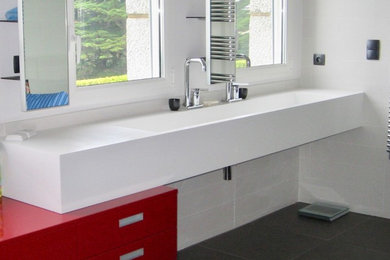 Cette image montre une salle de bain minimaliste avec des portes de placard rouges, une douche à l'italienne, un carrelage gris, des carreaux de céramique, un mur blanc, un sol en carrelage de céramique, une grande vasque et un sol noir.