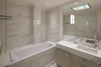 Cette image montre une salle de bain principale traditionnelle de taille moyenne avec un plan de toilette en marbre, une baignoire encastrée, un carrelage blanc, un carrelage de pierre, un mur beige, un sol en marbre et un lavabo encastré.