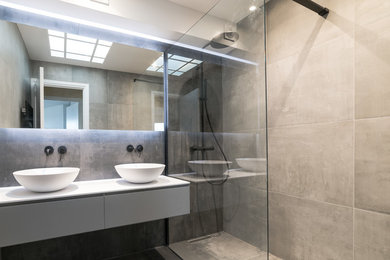 Exemple d'une petite salle de bain principale moderne avec des portes de placard grises, une douche à l'italienne, un carrelage gris, des carreaux de céramique, un mur gris, un sol en carrelage de céramique, une vasque, un plan de toilette en surface solide, un sol gris, aucune cabine et un plan de toilette blanc.
