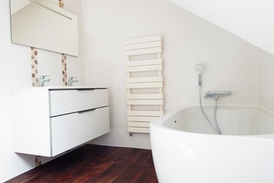 Idée de décoration pour une salle d'eau design de taille moyenne avec une baignoire d'angle, un carrelage blanc, un sol marron et un plan de toilette blanc.