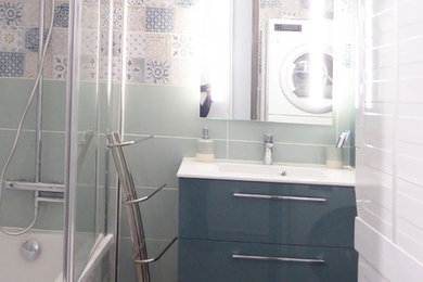 Exemple d'une salle d'eau moderne de taille moyenne avec un carrelage beige, un carrelage blanc, un carrelage bleu, un carrelage vert, des carreaux de béton, un placard à porte affleurante, des portes de placard bleues, une baignoire encastrée, un combiné douche/baignoire, WC séparés, un mur vert, un sol en carrelage de céramique, un lavabo suspendu, un sol marron, une cabine de douche à porte battante et un plan de toilette blanc.