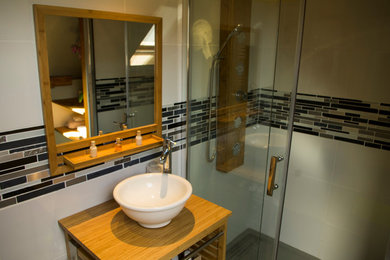 Cette image montre une petite salle d'eau design en bois clair avec un placard sans porte, un mur blanc, sol en stratifié et un plan de toilette en bois.