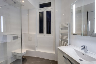 Idées déco pour une douche en alcôve principale de taille moyenne avec un placard à porte affleurante, des portes de placard blanches, WC suspendus, un carrelage blanc, un mur blanc, un lavabo encastré et un plan de toilette blanc.