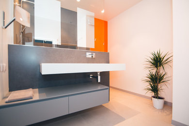 Photo of a medium sized contemporary ensuite bathroom in Toulouse with a built-in shower, grey tiles, cement tiles, orange walls, ceramic flooring, a console sink and grey floors.