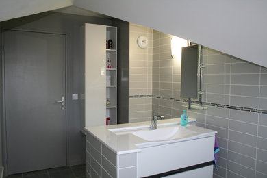Aménagement d'une salle de bain principale moderne de taille moyenne avec des portes de placard blanches, une baignoire encastrée, un combiné douche/baignoire, WC à poser, un carrelage gris, un carrelage de pierre, un mur gris et une grande vasque.
