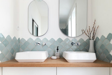 Exemple d'une salle de bain scandinave de taille moyenne avec un carrelage bleu, un mur blanc, un plan vasque, un plan de toilette en bois, un sol gris, un placard à porte plane, des portes de placard blanches et meuble double vasque.