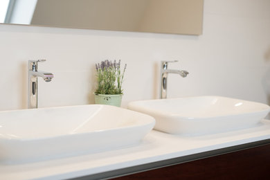 ブレストにあるコンテンポラリースタイルのおしゃれな浴室 (大型浴槽、壁掛け式トイレ、白いタイル、セラミックタイル、クッションフロア、横長型シンク、珪岩の洗面台、グレーの床) の写真