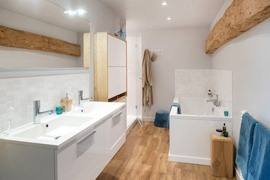 Exemple d'une grande salle de bain principale tendance avec des portes de placard blanches, une baignoire encastrée, une douche ouverte, un mur gris, un sol en bois brun, un lavabo encastré, un sol marron, une cabine de douche à porte battante et un plan de toilette blanc.