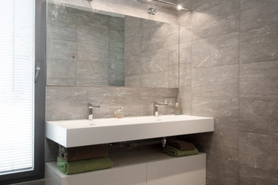 Idées déco pour une salle de bain moderne avec des portes de placard blanches et un carrelage gris.