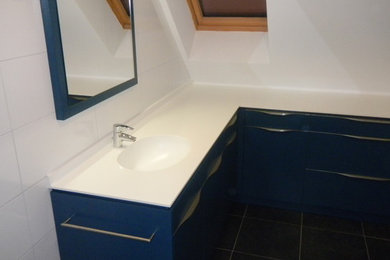 Idées déco pour une grande salle de bain contemporaine avec un placard à porte affleurante, des portes de placard bleues et un plan de toilette en surface solide.
