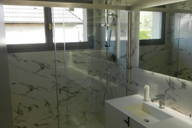 Cette image montre une petite salle d'eau minimaliste avec une douche à l'italienne, un carrelage blanc, des carreaux de céramique, un mur blanc, un sol en carrelage de céramique, un lavabo intégré et un plan de toilette en surface solide.