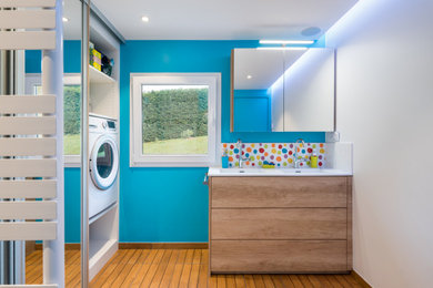 Cette photo montre une salle de bain principale tendance en bois brun de taille moyenne avec un placard à porte plane, un mur bleu, un lavabo intégré, un sol marron, un plan de toilette blanc et meuble-lavabo sur pied.