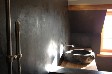 Cette image montre une grande douche en alcôve principale design avec un lavabo posé, un placard sans porte, un plan de toilette en béton, WC suspendus, une plaque de galets, un mur gris et un sol en galet.