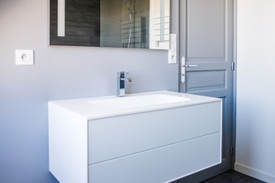 Réalisation d'une salle de bain design avec un carrelage gris, des carreaux de céramique, un mur gris, un sol en carrelage de céramique et un lavabo suspendu.
