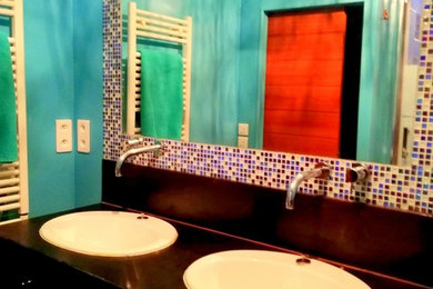 Exemple d'une petite salle de bain principale tendance avec un placard à porte vitrée, des portes de placard marrons, un carrelage bleu, un carrelage en pâte de verre, un mur bleu, parquet foncé, un lavabo encastré, un plan de toilette en bois, un sol marron et un plan de toilette marron.