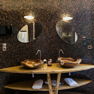 Réalisation d'une grand salle d'eau ethnique avec un placard sans porte, des portes de placard en bois brun, un carrelage marron, un carrelage noir, carrelage en mosaïque, un sol en carrelage de céramique, une vasque et un plan de toilette en bois.