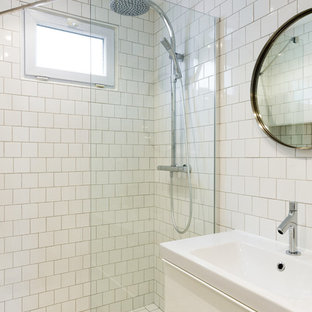 Cette image montre une salle d'eau nordique de taille moyenne avec des portes de placard blanches, un carrelage blanc, un placard à porte plane, une douche à l'italienne, des carreaux de porcelaine, un mur blanc, un sol en carrelage de porcelaine, un plan vasque, un plan de toilette en surface solide, un sol blanc, une cabine de douche à porte battante et un plan de toilette blanc.