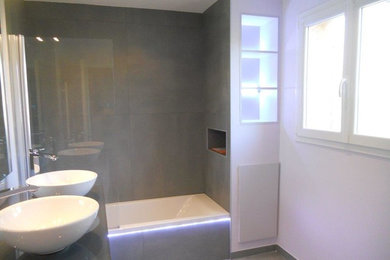 Cette photo montre une salle de bain principale moderne de taille moyenne avec des portes de placard blanches, une baignoire encastrée, un carrelage gris, un mur blanc, un lavabo posé, un plan de toilette en quartz, un sol gris et un plan de toilette gris.
