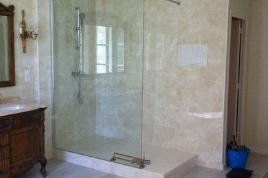 Cette photo montre une grande salle d'eau tendance avec une douche ouverte, un carrelage beige, des carreaux de céramique, un plan vasque et un plan de toilette en marbre.